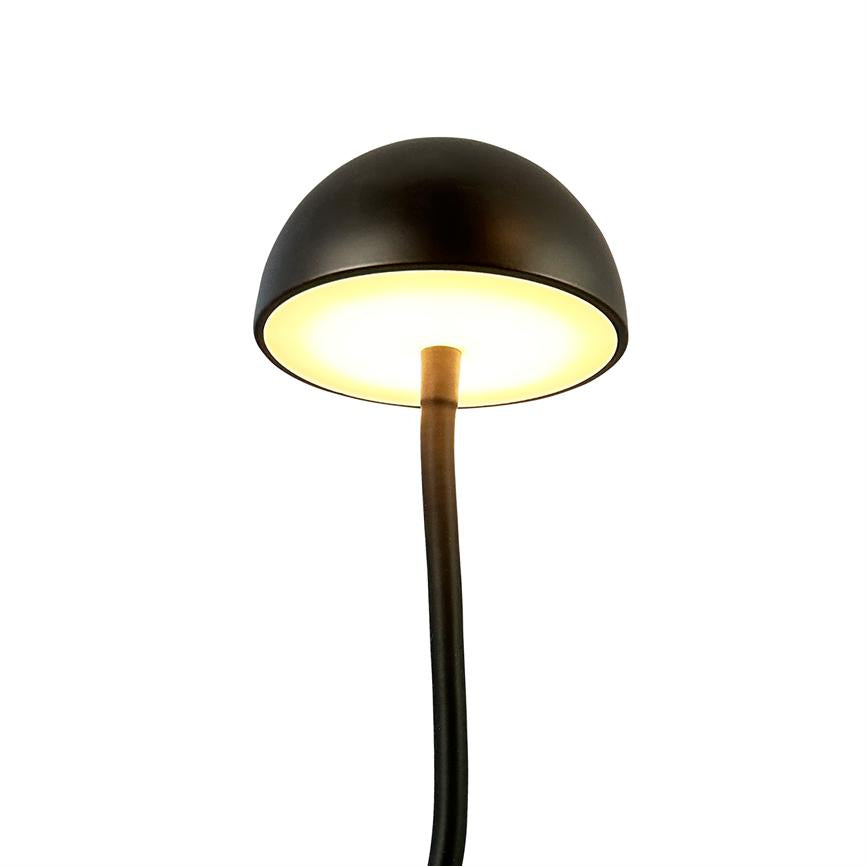 Sort, halvkugleformet bordlampe udsender varmt, diffust lys; monteret på en buet sort stilk og placeret foran en ensartet hvid baggrund.
