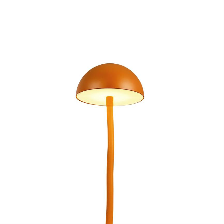 En orange lampe med halvkugleformet skærm udsender varmt, diffust lys på en tynd, let buet stang mod en ren hvid baggrund.