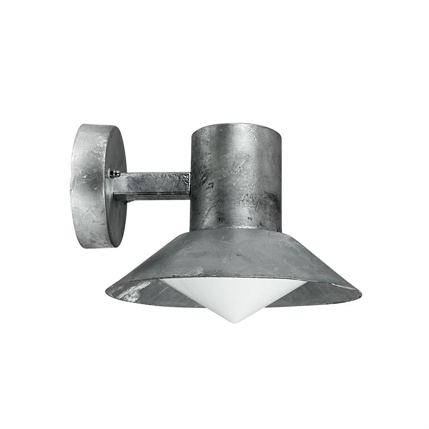 Væglampe: rå metalcylinder med bred, kegleformet skærm og hvid, pyramideformet diffuser; monteret på rundt vægbeslag via kort arm, vender nedad mod en neutral hvid baggrund.