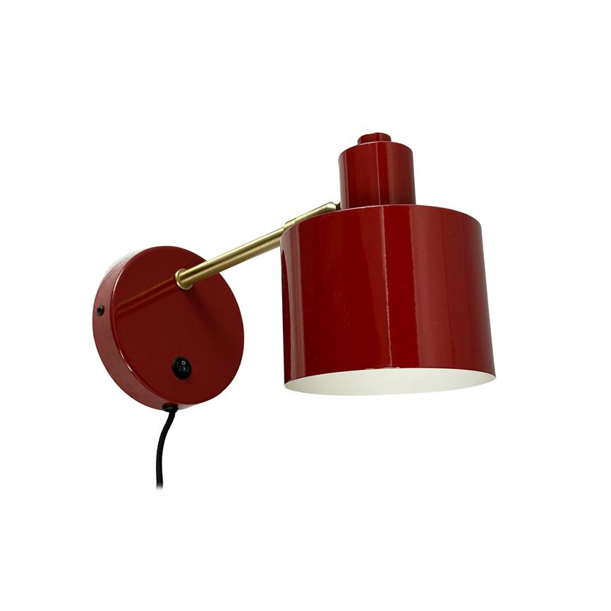 Rød metal væglampe monteret på rund vægplade; en messingarm holder en cylindrisk skærm, som peger nedad mod en neutral hvid baggrund.