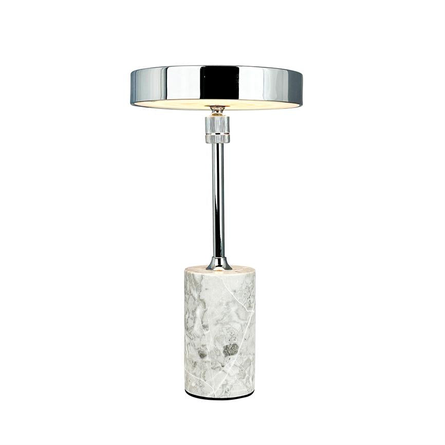 Bordlampe med cylindrisk marmorfod og slank kromstang, udsender blødt, nedadrettet lys fra en bred, blank kromskærm, vist isoleret mod en ensartet hvid baggrund.