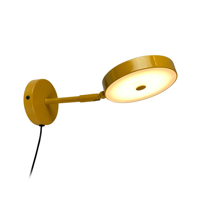 Væglampe i gul metal stråler varmt lys fra en rund LED-skive, monteret på en udadgående arm fra et rundt vægbeslag med en synlig sort ledning.