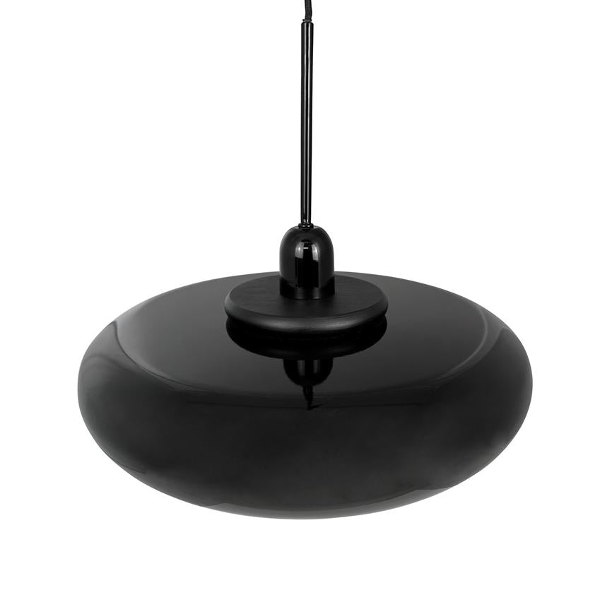 Sort pendel-lampe hænger i en tynd ledning over hvid baggrund; blank, bred, lav, rund skærm med glans og bløde refleksioner, i en minimalistisk studieopstilling.