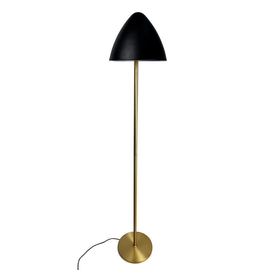 Gulvlampe står oprejst, med slankt messingstativ og sort kuppel, synlig sort ledning ved rund messingfod, mod ensartet hvid baggrund.