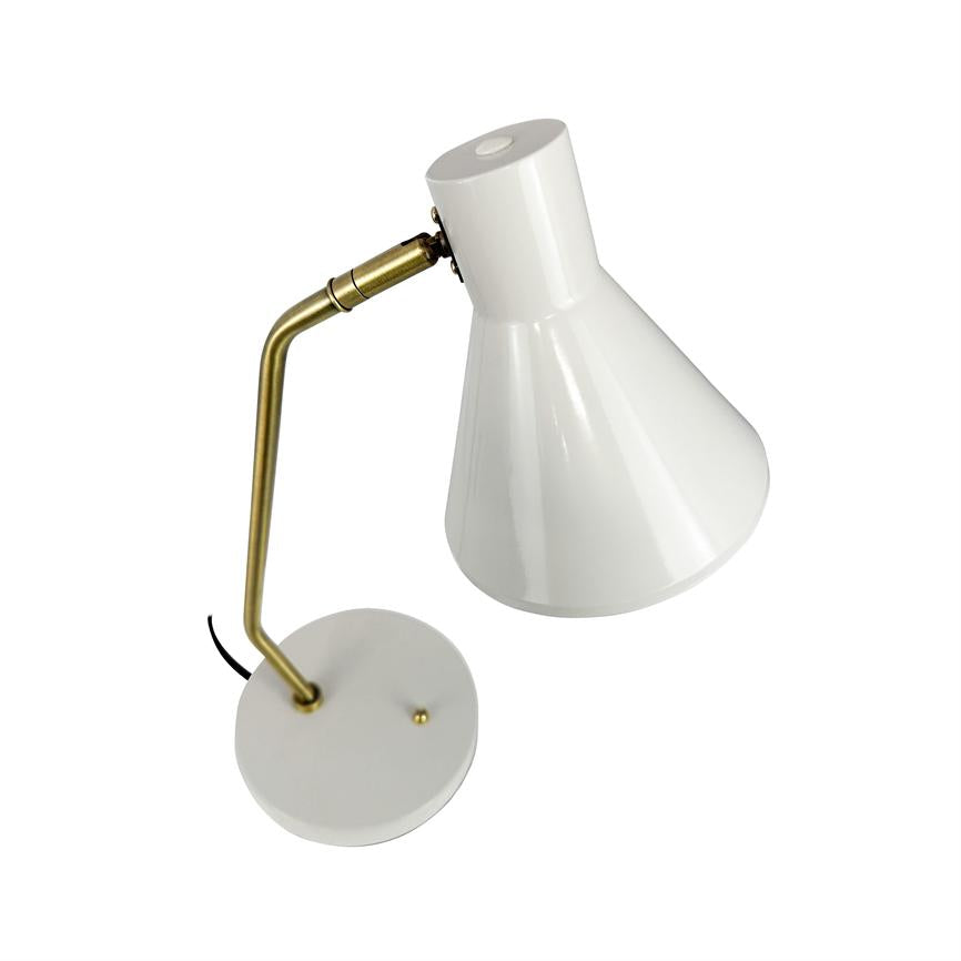 Hvid bordlampe med kegleformet skærm og messingfarvet vinkelarm; skærmen er rettet nedad, monteret på rund fod med tændknap og sort ledning, isoleret på hvid baggrund.