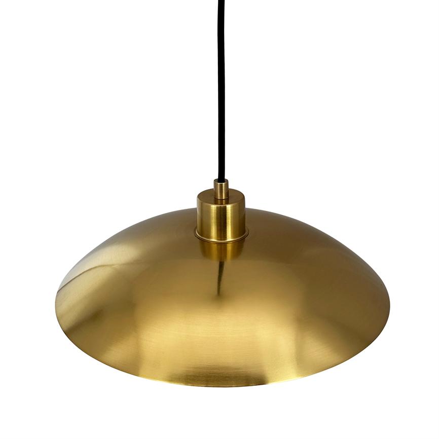 En rund, messingfarvet pendellampe hænger i en sort ledning; dens brede, skålformede metalskærm reflekterer blødt lys og står isoleret mod en neutral, hvid baggrund.