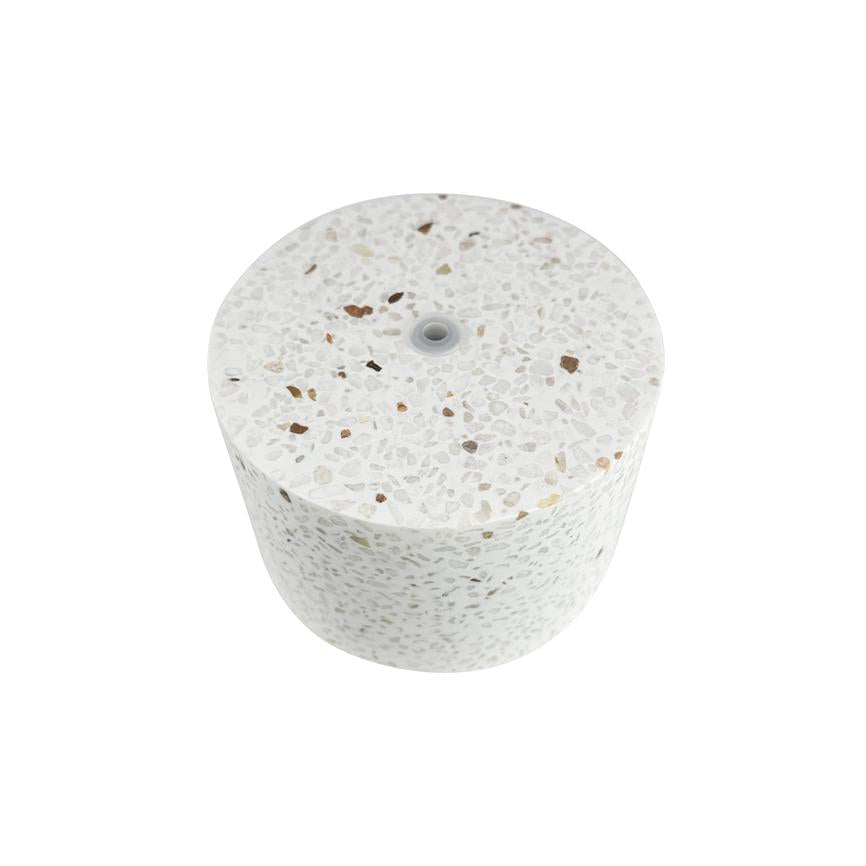 Cylindrisk terrazzo-blok med hvide, beige og brune stenindslag, med lille centralt hul forsynet med gummiring; hviler isoleret på en ren, hvid baggrund.
