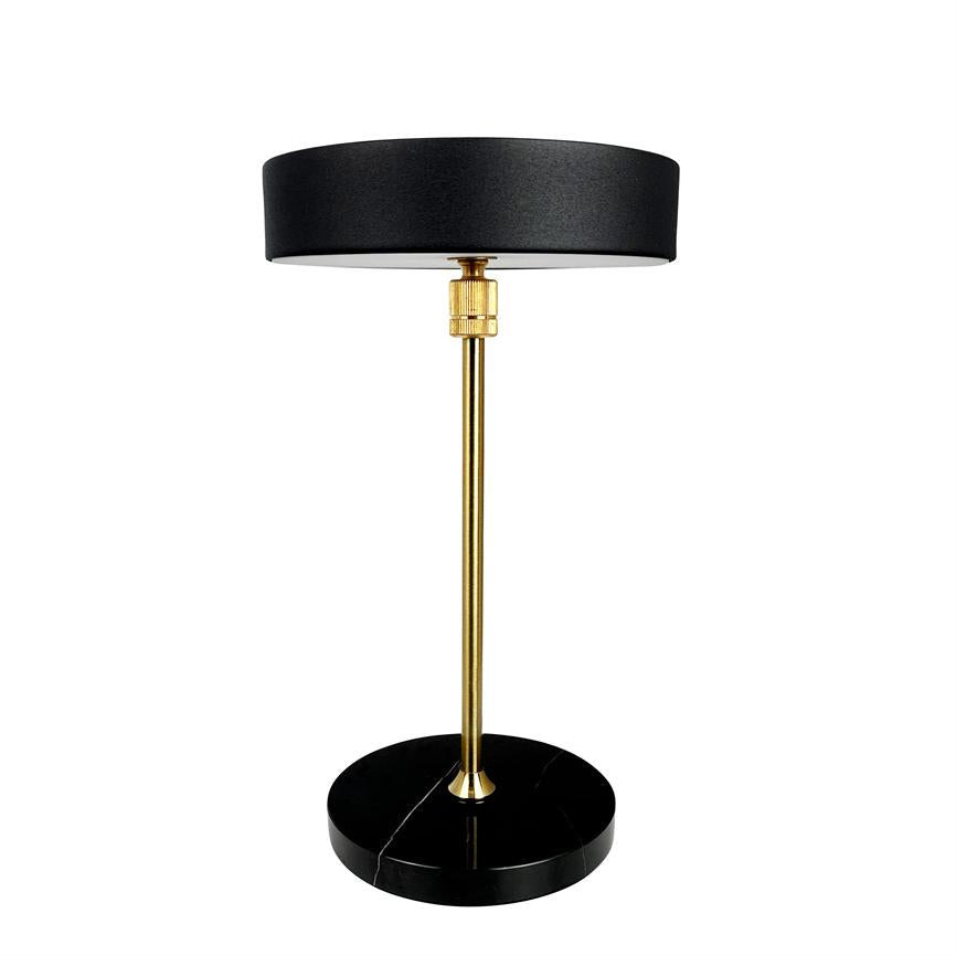 Bordlampe står med en slank messingstang og sort cylindrisk skærm; den hviler på en rund, sort marmorbase mod en ensartet hvid baggrund.
