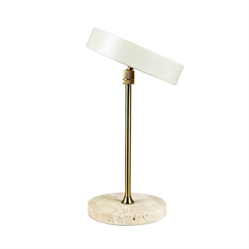 Bordlampe står, dens justerbare runde hvide skærm er let vinklet på en slank messingstang, monteret på en rund lys travertinfod mod hvid baggrund.