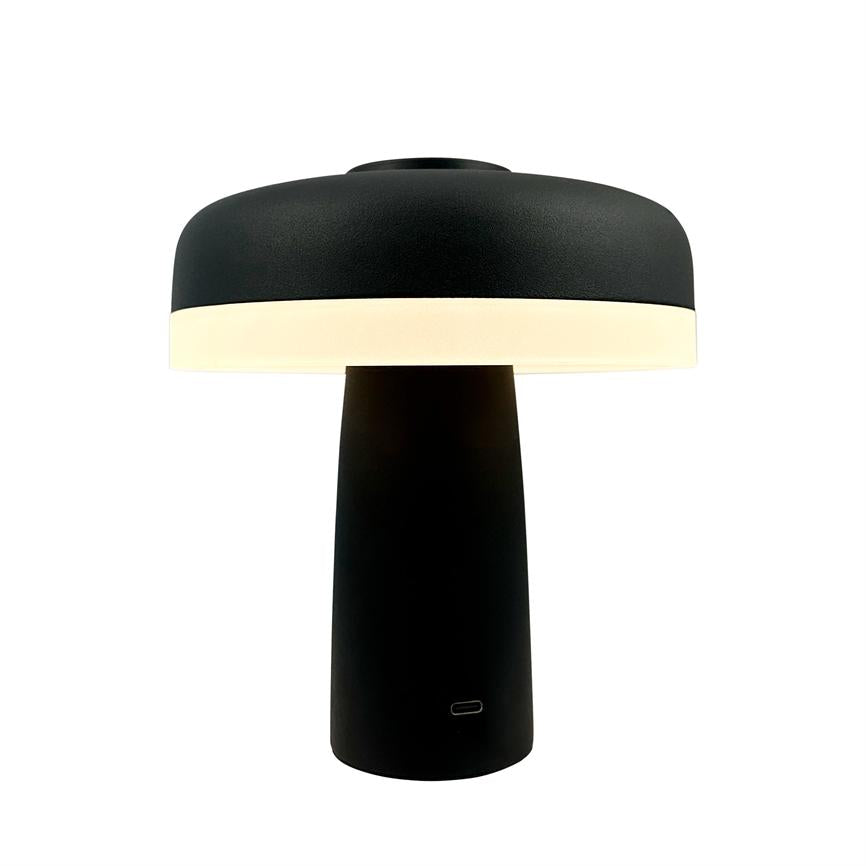 Bordlampe med sort, svampelignende skærm og cylindrisk fod; skærmens nederste kant udsender blødt, varmt lys, og en lille USB-C-port ses i fodens front; neutral hvid baggrund.