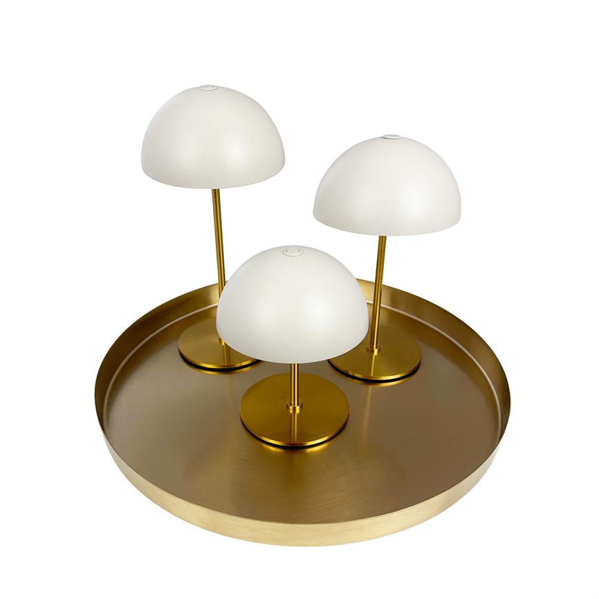 Tre små bordlamper med hvide kupler og gyldne standere står samlet på et rundt, mat gyldent metalfad mod en neutral hvid baggrund.