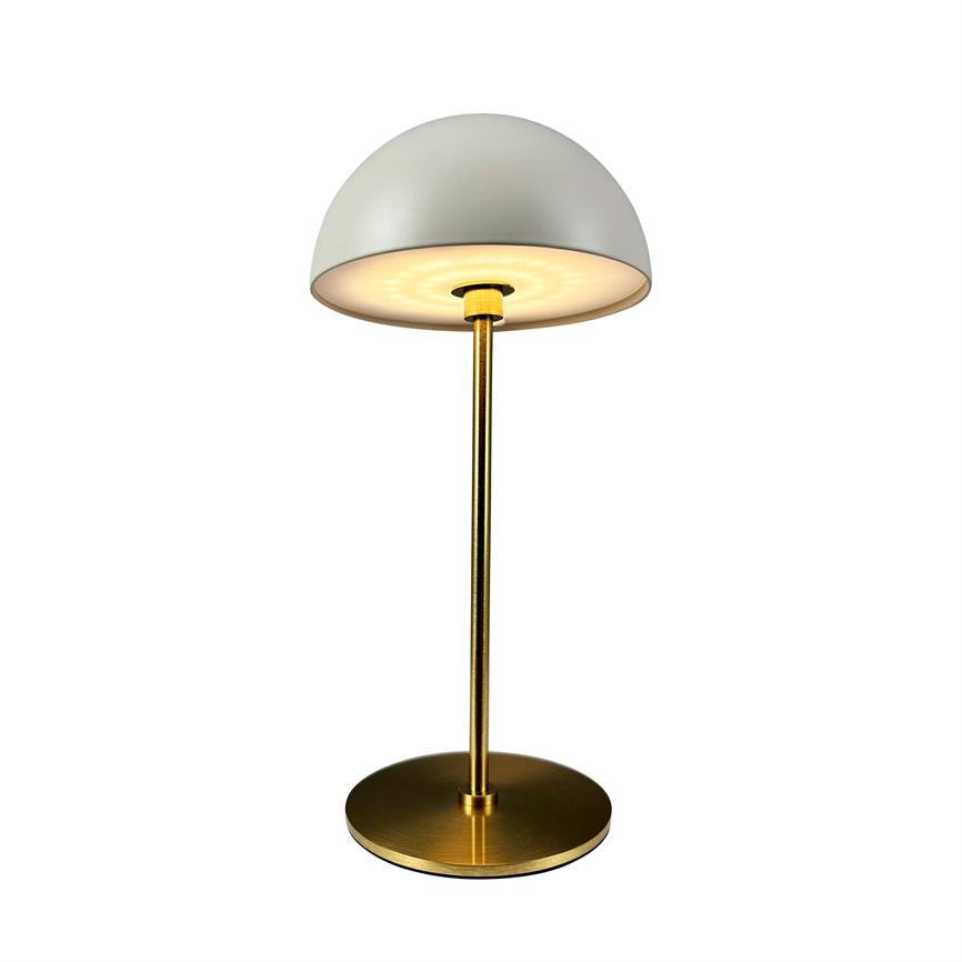 Bordlampe udsender en varm glød gennem en hvid kuppelskærm, står på en slank messingstang med rund messingfod og er placeret mod en neutral hvid baggrund.