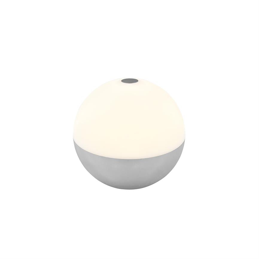 Rund bordlampe (halvkugle) lyser blødt; øverste hvide halvdel udsender varmt lys, nederste halvdel er metalgrå; lille sort trykknap på toppen, placeret på hvid baggrund.