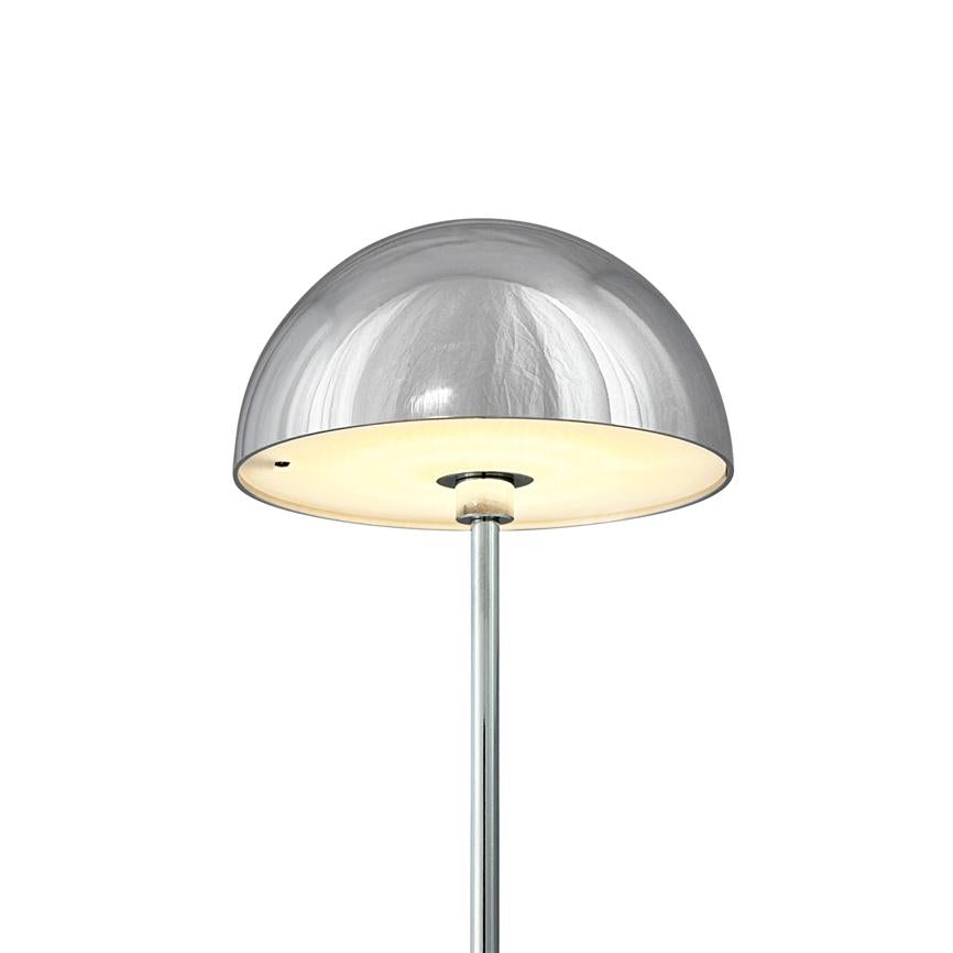 Halvkugleformet gulvlampe lyser blødt nedad, med skinnende kromskærm og hvid diffuser, monteret på en slank metalstang mod en tom hvid baggrund.