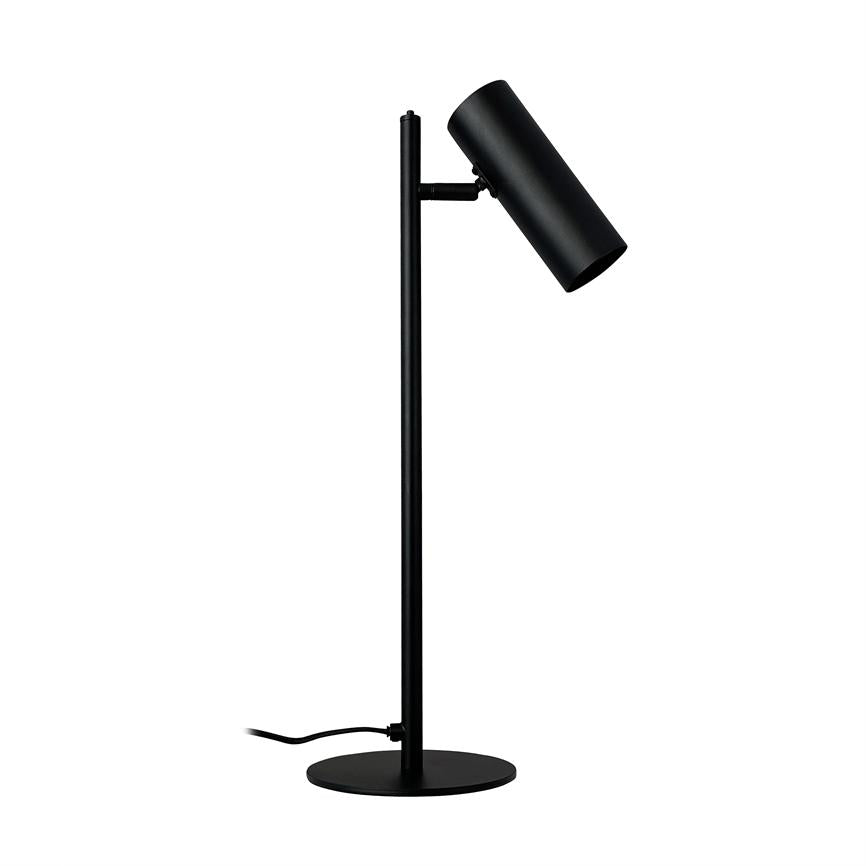 Sort bordlampe med cylindrisk skærm, vinklet nedad; står på slank lodret stang og rund fod, med synlig strømledning, placeret foran en hvid, neutral baggrund.