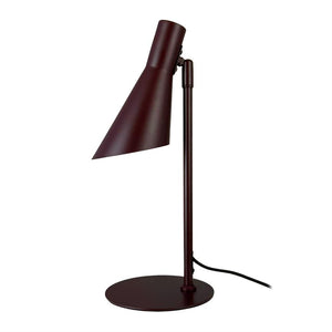 Bordlampe med mørkerød, skrå konisk skærm, står på slank lodret stang og rund fod; skærmen peger nedad, sort ledning løber langs foden; hvid baggrund.
