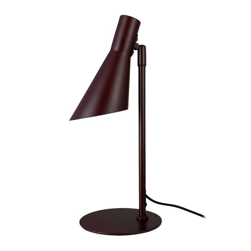 Bordlampe med mørkerød, skrå konisk skærm, står på slank lodret stang og rund fod; skærmen peger nedad, sort ledning løber langs foden; hvid baggrund.