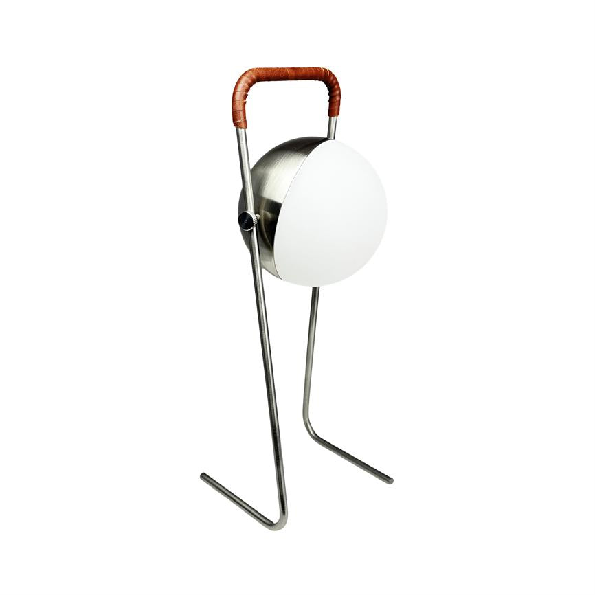 Lampe står på to buede metalben, med rund hvid glasskærm og rund metalkrop, let vinklet; øverste greb indbundet i brunt læder. Hvid, ensartet baggrund.