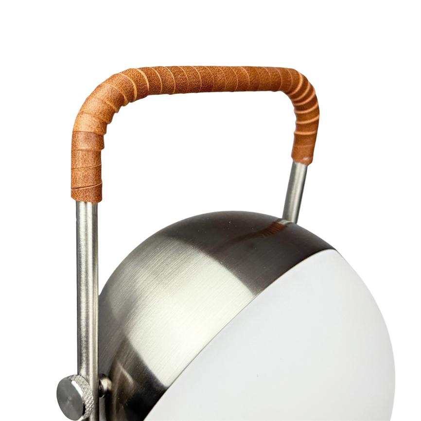 Bordlampe med rund, børstet stål-krop og hvid kuppel; et brunt læderindpakket buet håndtag er monteret over toppen, afbildet mod en ensartet hvid baggrund.