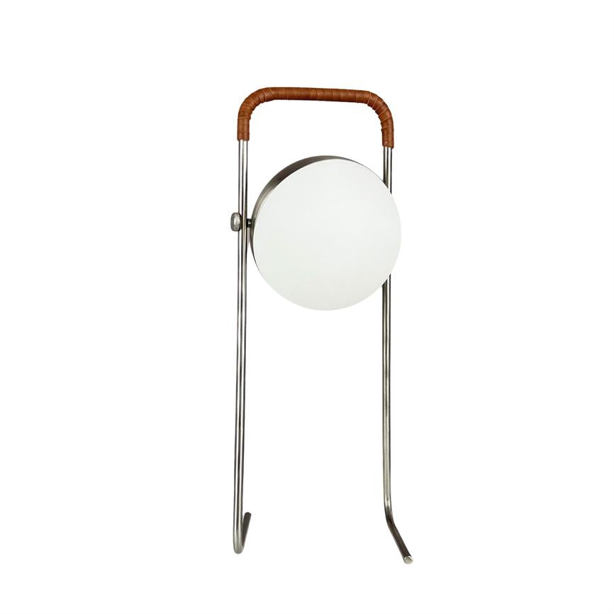 Rund lampe monteret i et slankt metalstativ, hviler på to buede ben; hvid skærm og brunt læderviklet håndtag øverst, placeret mod en ensartet hvid baggrund.