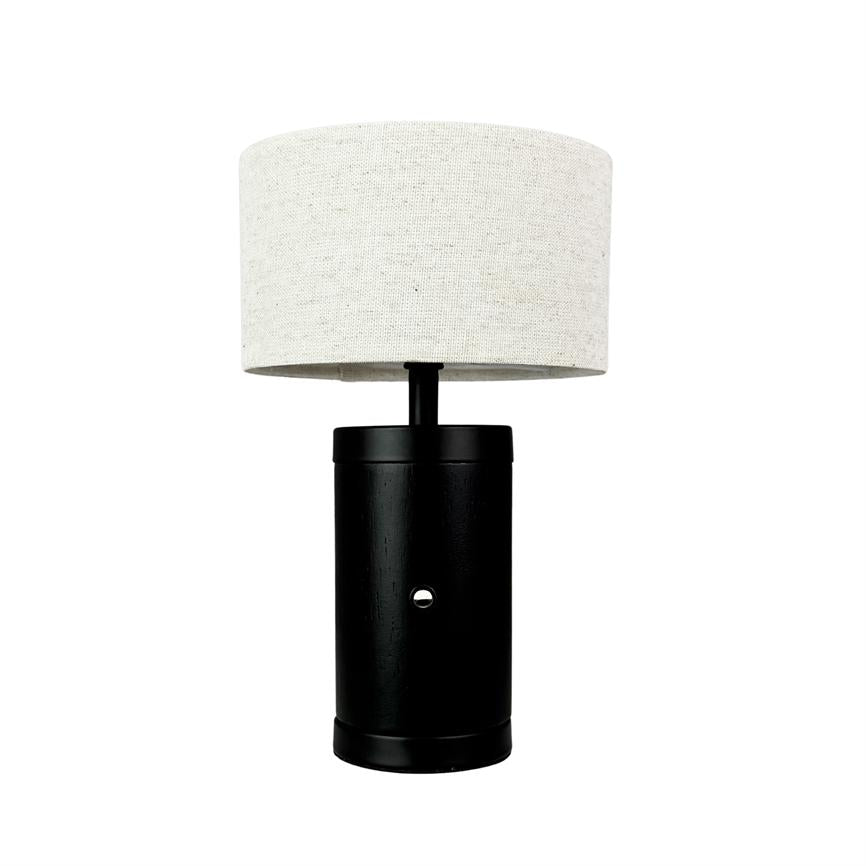 Lampe med cylindrisk sort fod og rund naturhvid stofskærm står centralt placeret på en ensartet hvid baggrund.