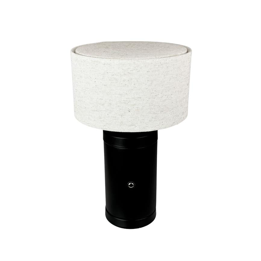 Lampe med cylindrisk sort metalbase, synlig rund knap og lys beige stofskærm står centreret på hvid baggrund.
