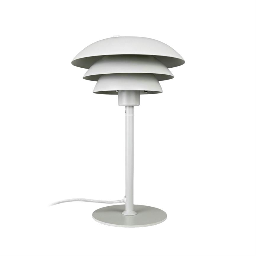 En hvid bordlampe med tre lagdelte skærme står på en slank stander og rund fod; ledning ligger bøjet ved siden af, mod hvid baggrund.